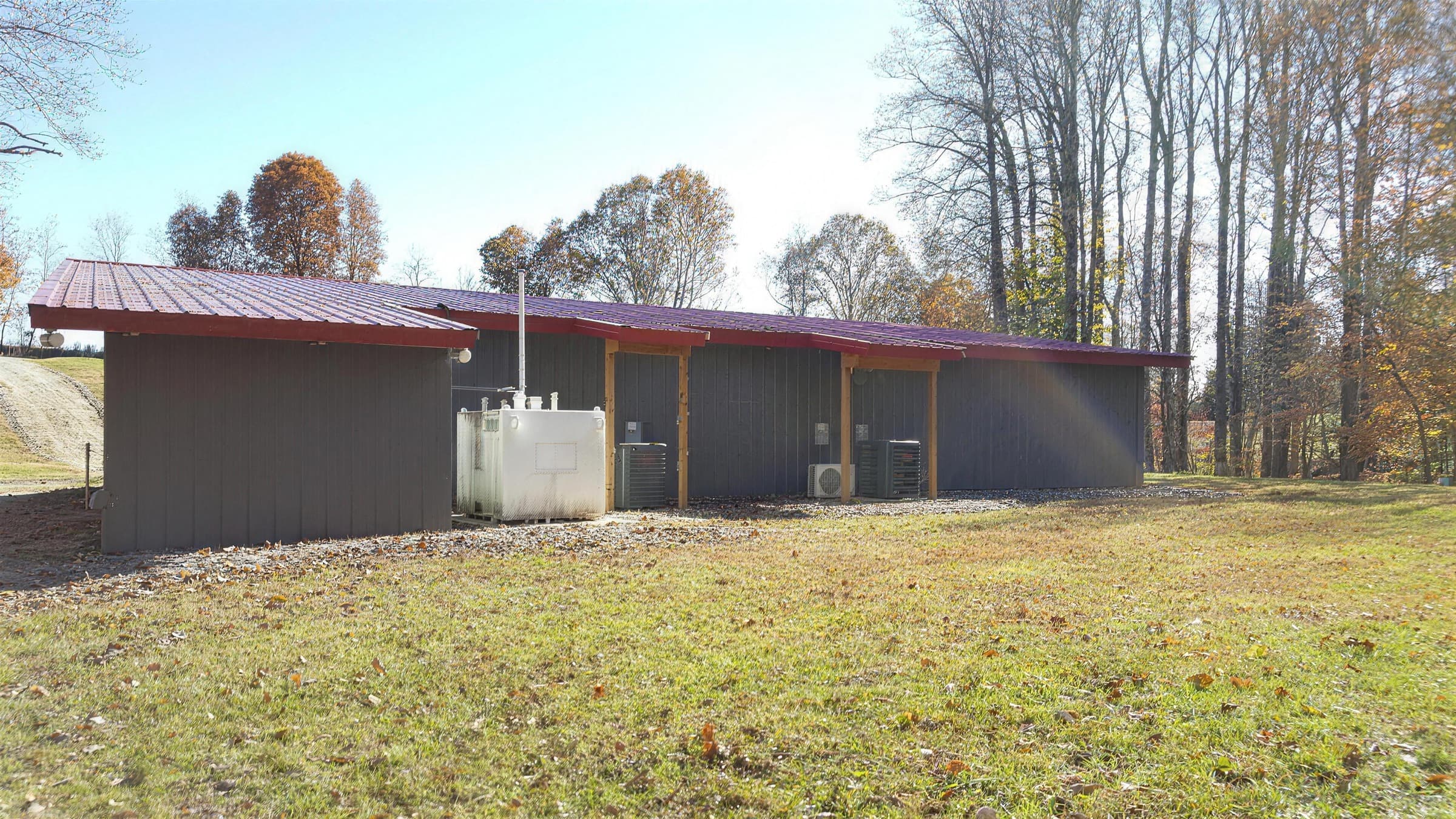 The grow house at Dubia Growers, a long low building with a red roof, surrounded by autumn woodland in Amherst, Virginia